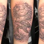 Tatouage marin sur mesure représentant une tortue marine nageant sous un crabe dans un décor sous-marin réaliste réalisé en noir et gris.